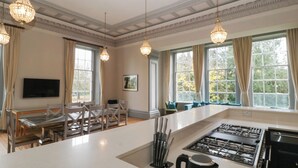 A spacious kitchen with a central island, modern appliances, and pendant lighting. - Frenchay Park House (Bristol)