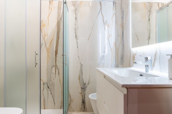 A modern bathroom with a glass shower enclosure, a white sink, and a marble backsplash. - Orsanmichele Suite - Florence (Firenze)
