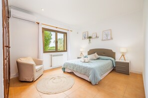 A bedroom with a bed, bedside tables, a chair, a window, and wall art. - Holiday Home 'Villa Cal Peso' with Mountain View, Wi-Fi and Air Conditioning (Illes Balears)