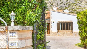 A stone wall with a metal gate, a white building with a tiled roof, and a paved pathway. - Holiday Home 'Villa Cal Peso' with Mountain View, Wi-Fi and Air Conditioning (Illes Balears)