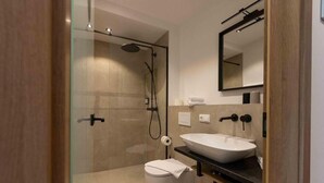 A modern bathroom with a glass-enclosed shower, a white toilet, and a large vessel sink. - Hotel und Landgasthof Zachschuster (Gaißach)