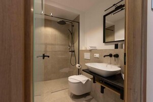 A modern bathroom with a glass-enclosed shower, a white toilet, and a large vessel sink.