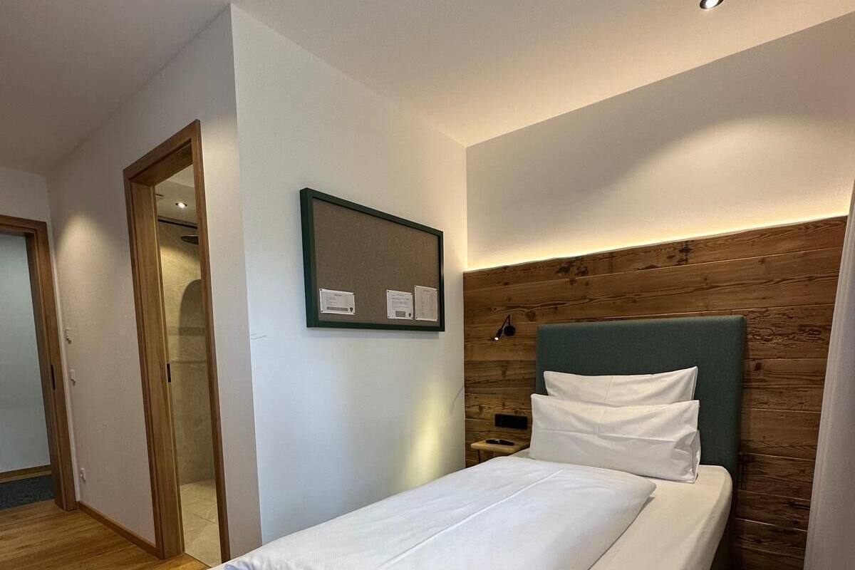 A modern bedroom with a large bed, wooden flooring, a wooden headboard, and a wall-mounted mirror.