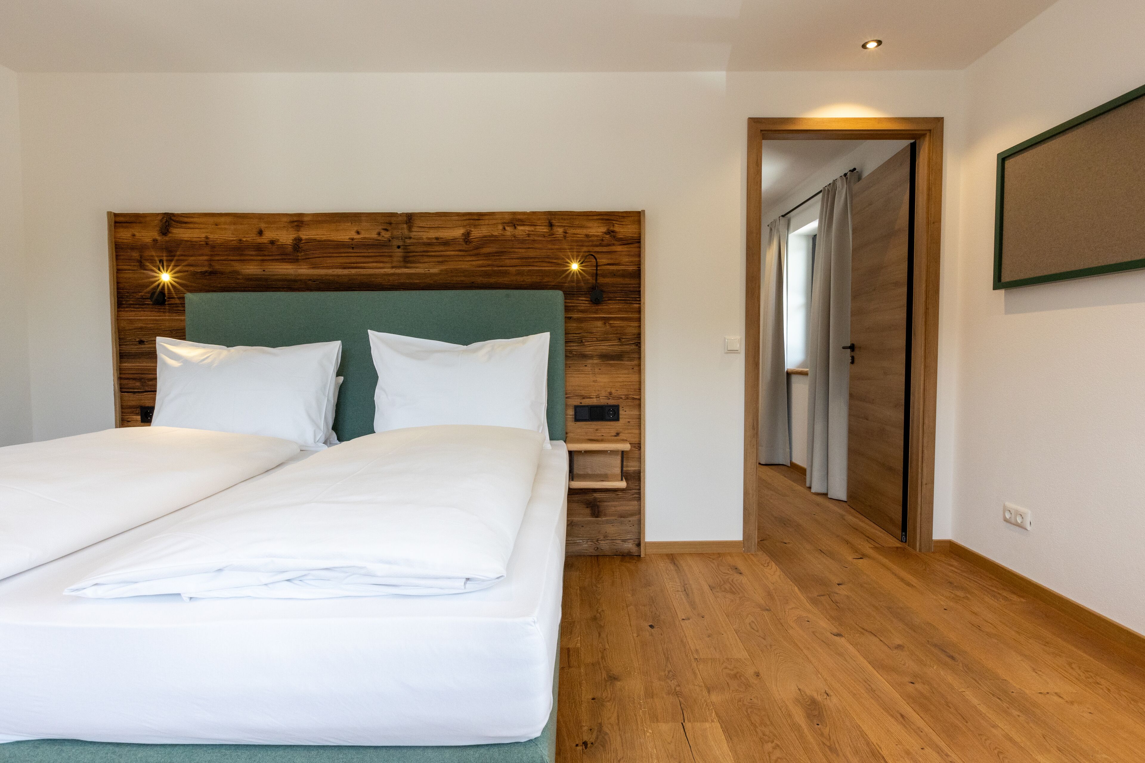 A double bed with a wooden headboard, a bedside table, and a nightstand.