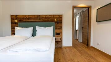 A double bed with a wooden headboard, a bedside table, and a nightstand.