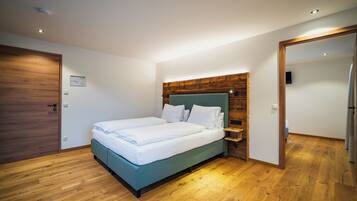 Ein Schlafzimmer mit Holzboden, einem Bett mit weißer Bettwäsche, einem Holz-Kopfteil und einem Nachttisch.