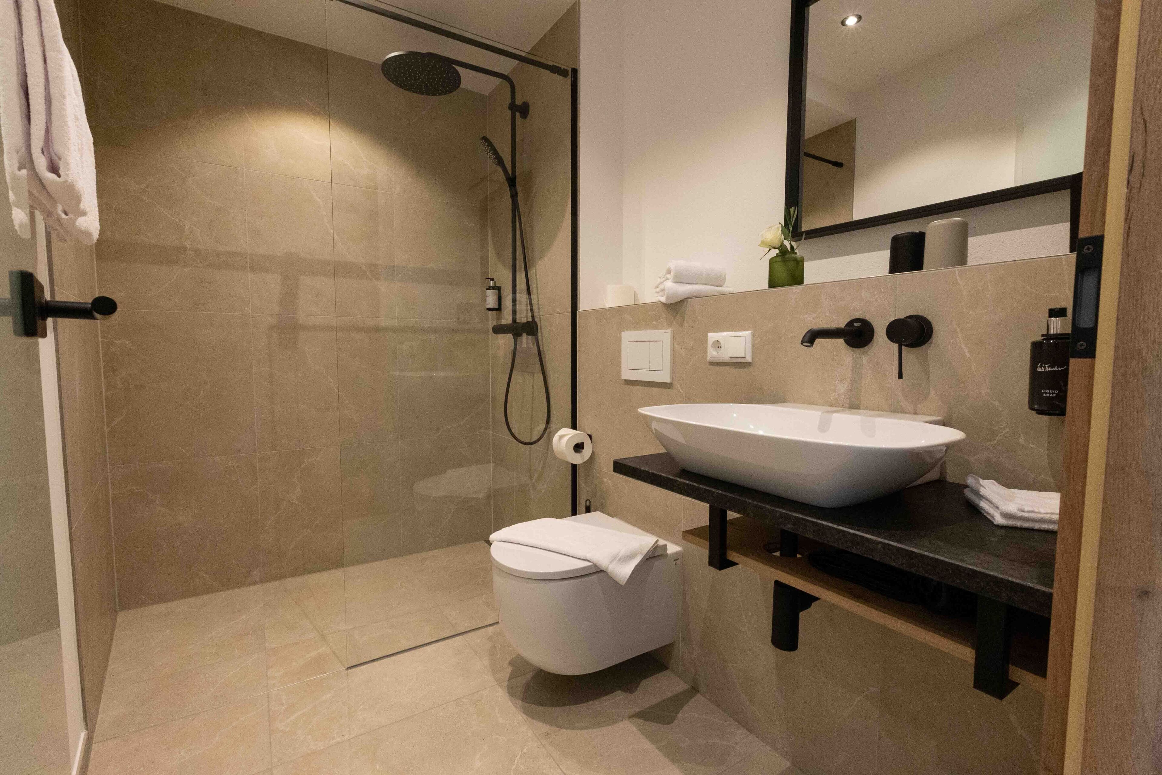 A modern bathroom with a glass-enclosed shower, a white toilet, and a large vessel sink.