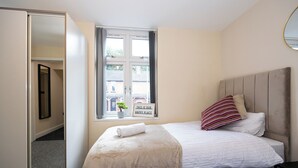 A bedroom with two beds, a window with a view, a mirror, and a sign on the window. - Cosy 4 Bed Townhouse Near Keele University and Royal Stoke Hospital (Newcastle-Under-Lyme)