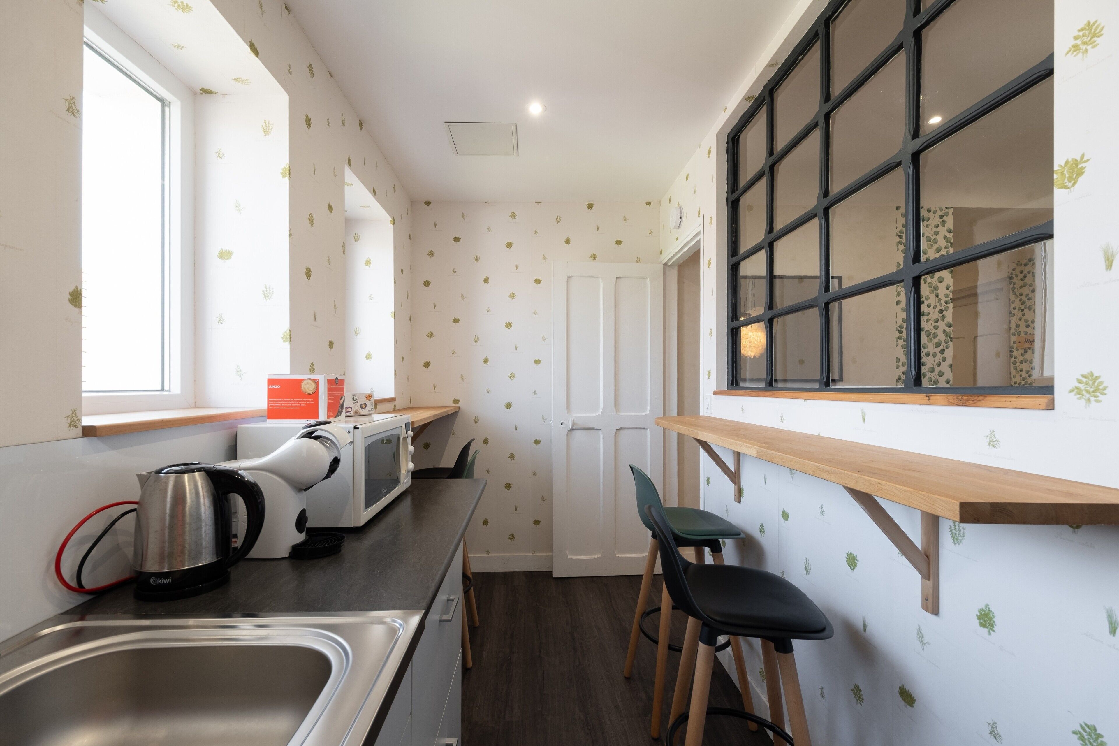 Cocina compacta con microondas, hervidor y lavabo.