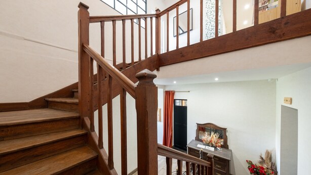 A wooden staircase leading to an upper floor with a desk and a vase of flowers in the lower area. - Mirabelle Room with Wi-Fi (Brû)