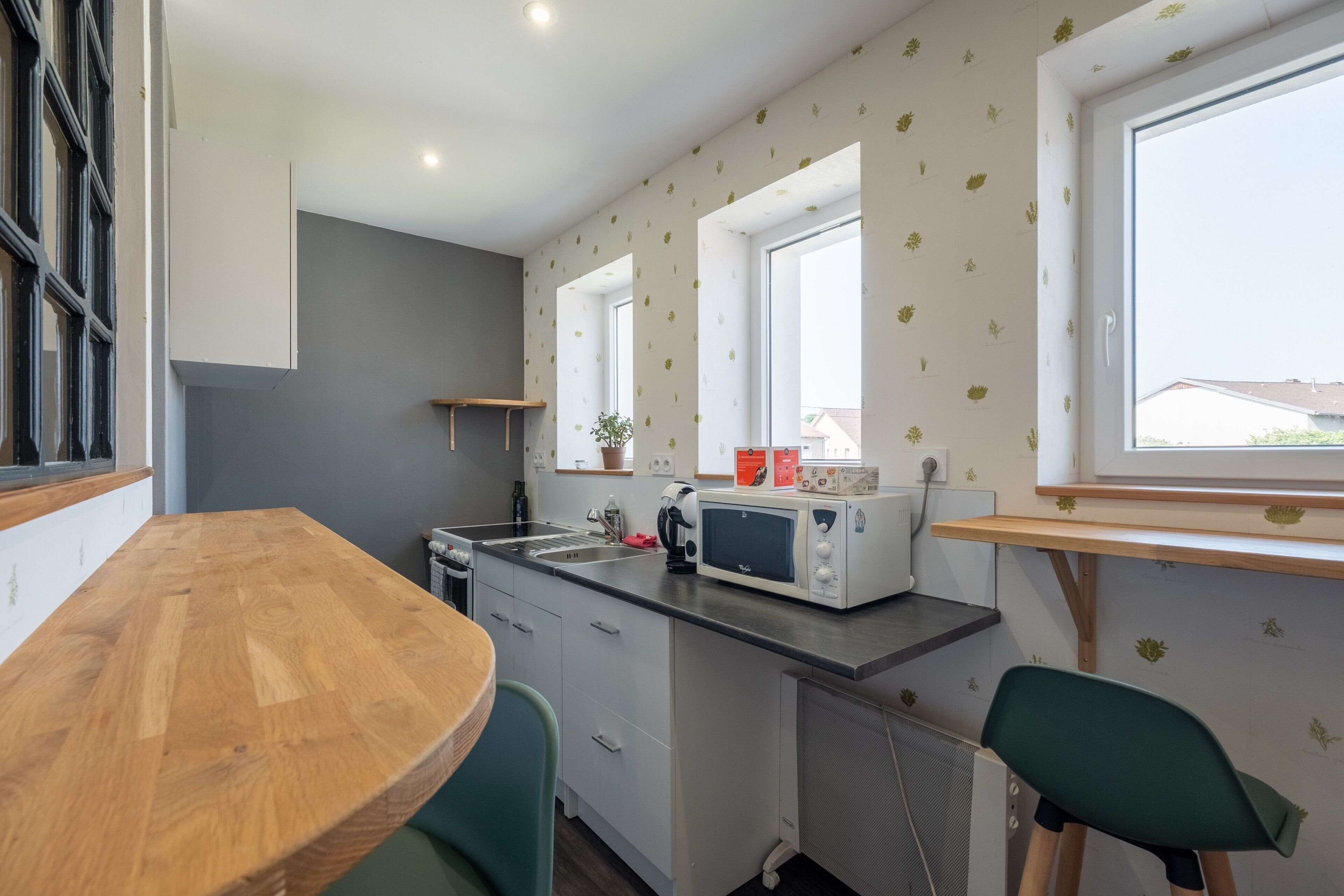 A compact kitchen with a wooden table, a microwave, and a window with a view.