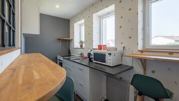 A compact kitchen with a wooden table, a microwave, and a window with a view.