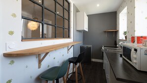 A compact kitchen with a window, a microwave, a sink, and two stools. - Mirabelle Room with Wi-Fi (Brû)