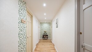 A hallway with wooden flooring, white walls, and a door with a nameplate. - Jonquille Room with Wi-Fi (Brû)