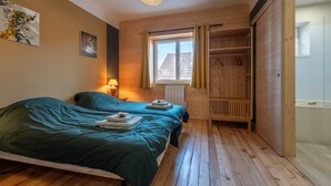 A room with two beds, a window with curtains, a radiator, and a wooden wardrobe. - Jonquille Room with Wi-Fi (Brû)