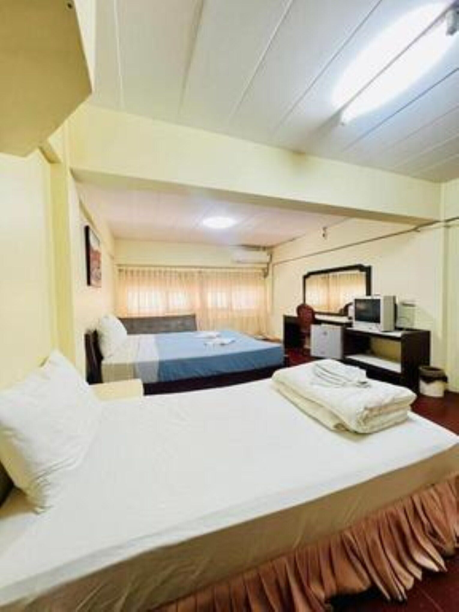 A hotel room with a single bed, a desk with a computer, and a television.