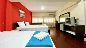 Habitación de hotel con dos camas, un escritorio y televisión, y una pared decorada en rojo.
