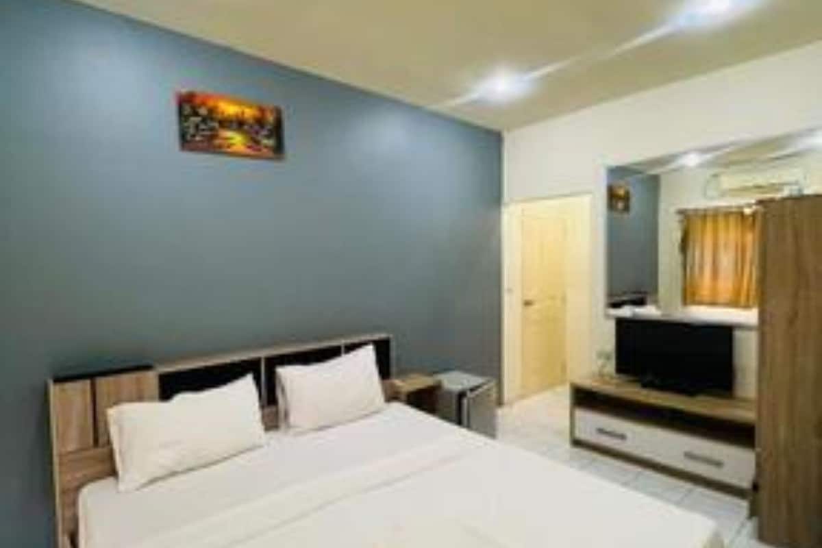 Habitación de hotel con cama, televisión, escritorio y espejo.