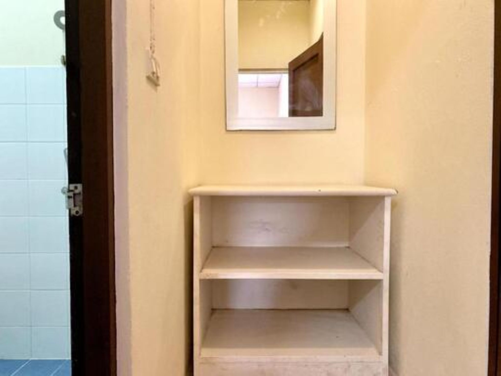 Een badkamer met een betegelde muur, een houten deur en een witte plankunit.