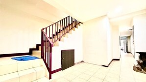 Un interior amplio con una escalera, piso de baldosas y una puerta que da a otra habitación.