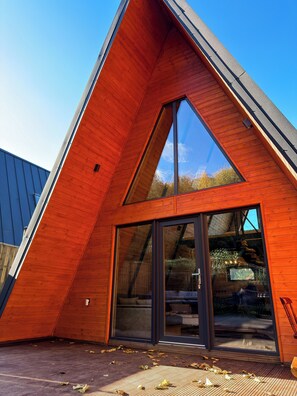 A modern building with a triangular roof and large glass doors. - Macko Cabin (Băile Tușnad)