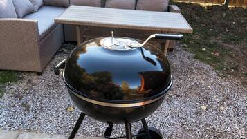 A barbecue grill with a lid, a metal handle, and a vent.