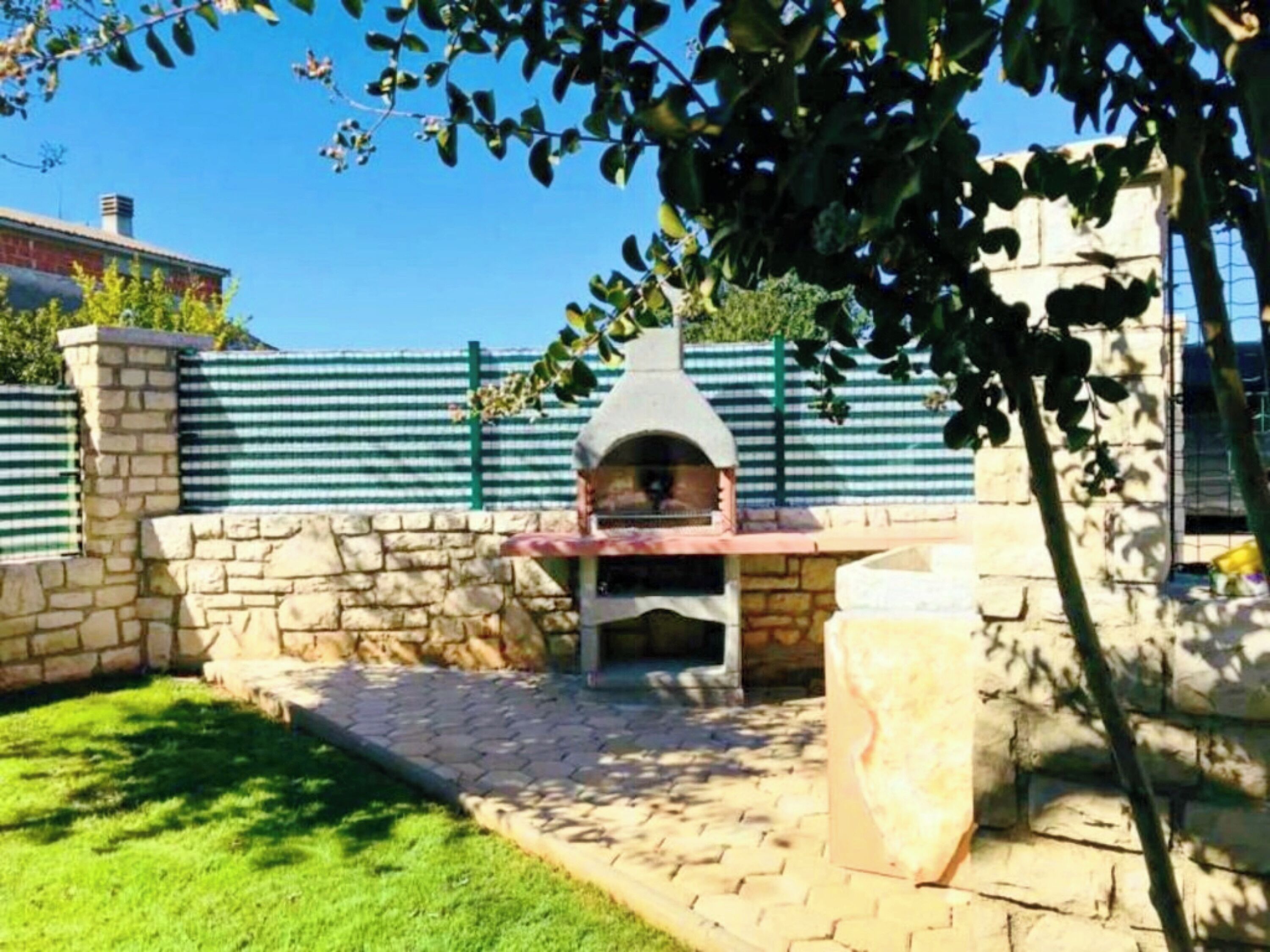 An outdoor brick patio with a stone wall and a pizza oven.