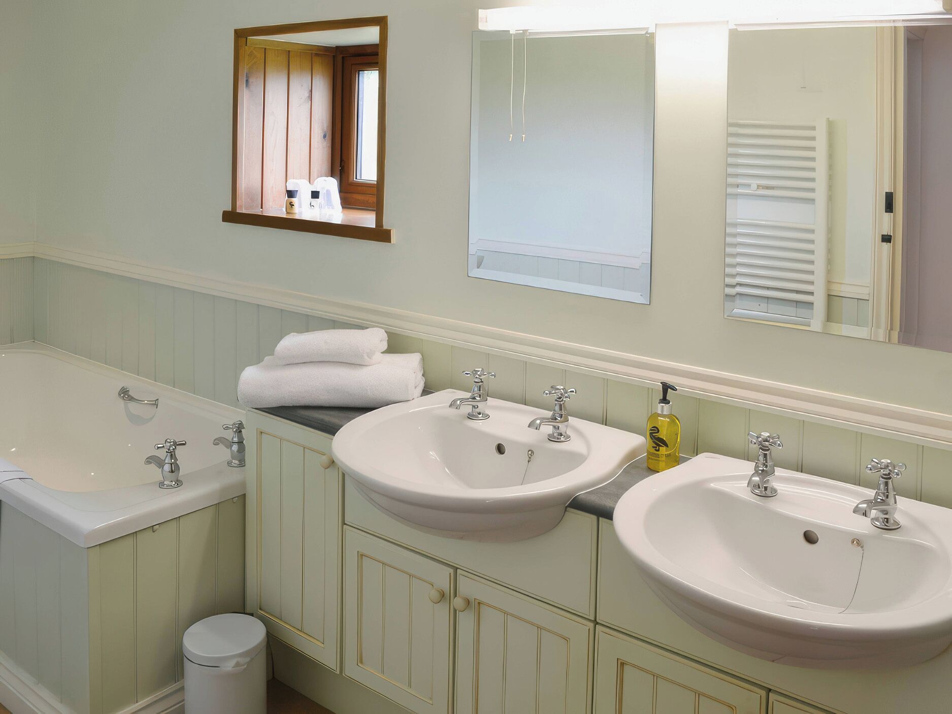 A bathroom with two sinks, a bathtub, and a mirror.