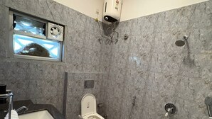 Ein Badezimmer mit Toilette, Waschbecken, Dusche und einer Wand-Klimaanlage.