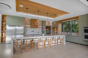 A modern kitchen with a central island, bar stools, pendant lighting, and a large window. - Vaquero Del Mar (La Dulce Vida, Hacienda Pinilla)
