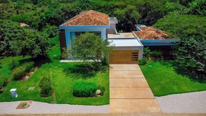 Una casa moderna con techo plano, garaje a la vista y césped cuidado.