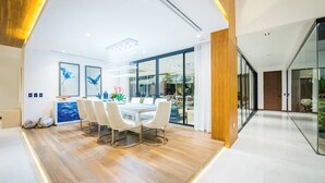Un comedor moderno con suelo de madera, sillas blancas y un panel de vidrio.