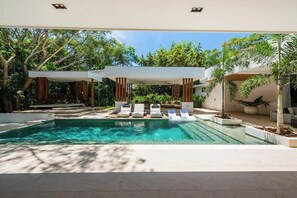 Ein moderner Poolbereich im Freien mit Liegestühlen und einer Pergola.