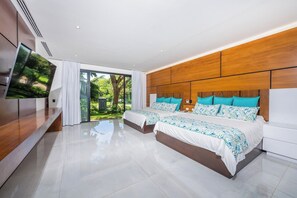 Un dormitorio moderno con dos camas, un televisor y un ventanal corredera a un jardín.