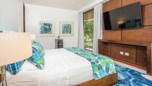 Habitación de hotel con una cama, un televisor montado en la pared y obras de arte.