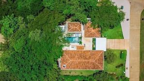 Ein modernes Haus mit Swimmingpool, umgeben von üppiger Vegetation.
