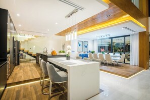 Eine moderne Küche mit einer zentralen Kochinsel, Barhocker und einem Essbereich mit Holztisch und Stühlen.