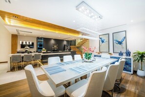 Un comedor moderno con una mesa larga, sillas y una araña.