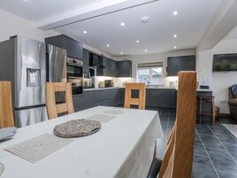Una cocina moderna con armarios oscuros, electrodomésticos de acero inoxidable y un comedor con mesa y sillas.