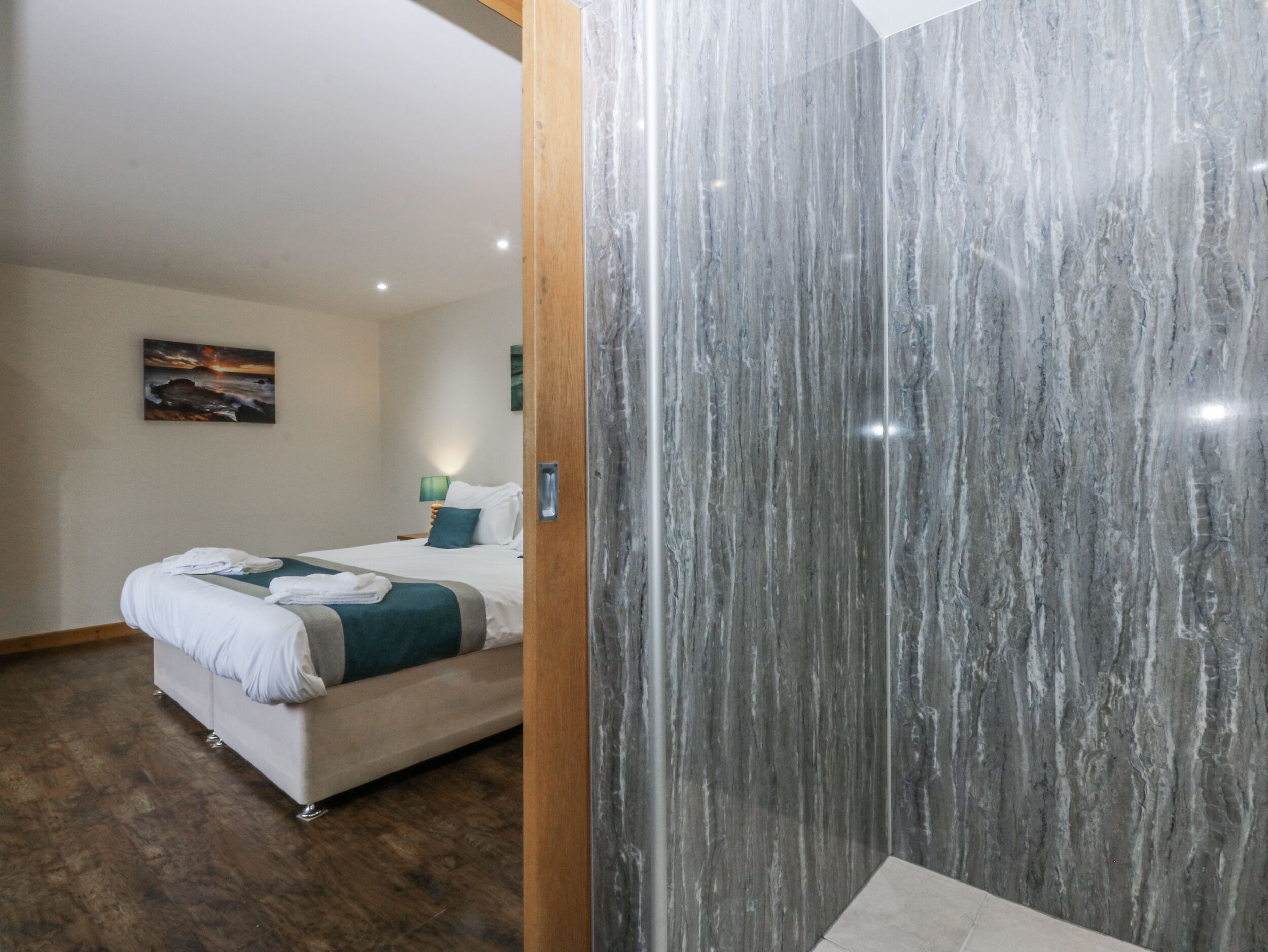 A hotel room with a bed, a wooden door, and a marble wall.