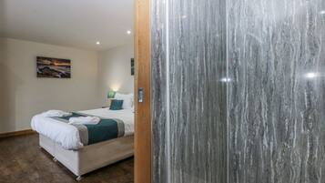 A hotel room with a bed, a wooden door, and a marble wall.