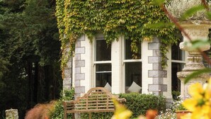 A building with a stone facade, large windows, and a bench in the foreground. - Horseshoe Cottage (Falmouth)