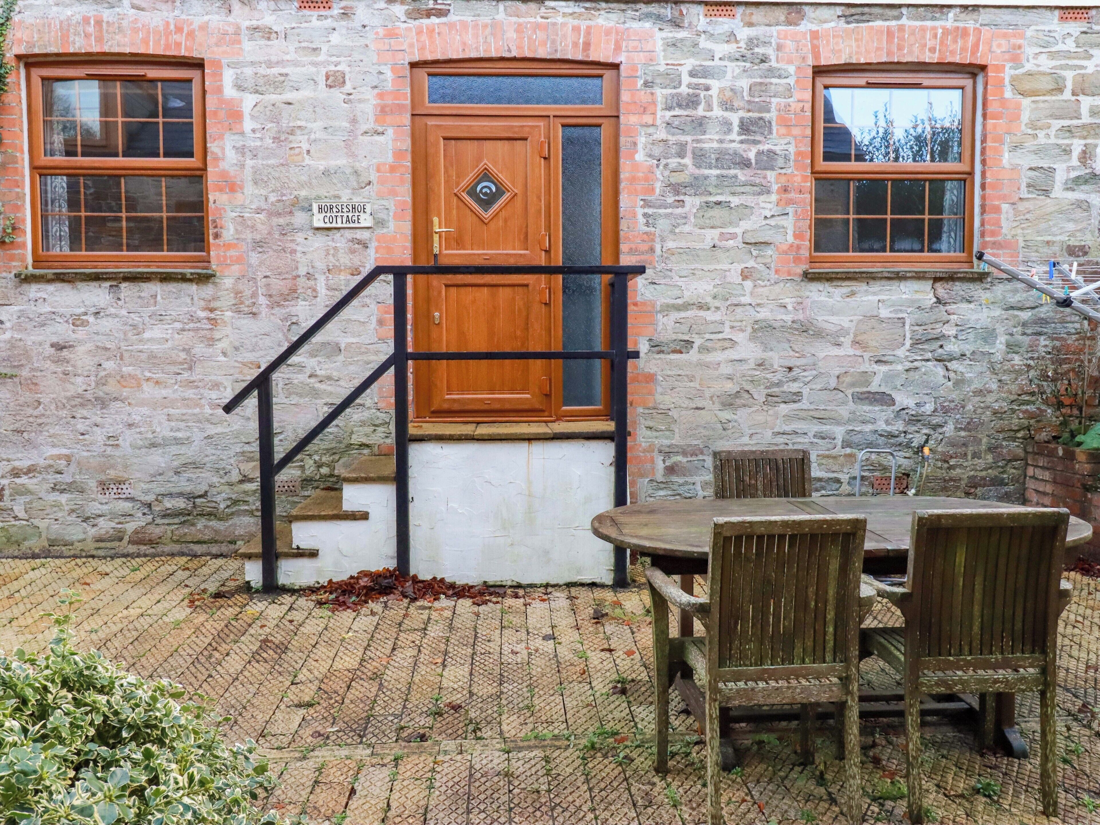 Un edificio de piedra con una puerta de madera, una escalera y una mesa con sillas.