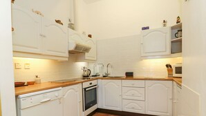 Eine kompakte Küche mit weißen Schränken, einem Geschirrspüler, einem Backofen und einer Mikrowelle.