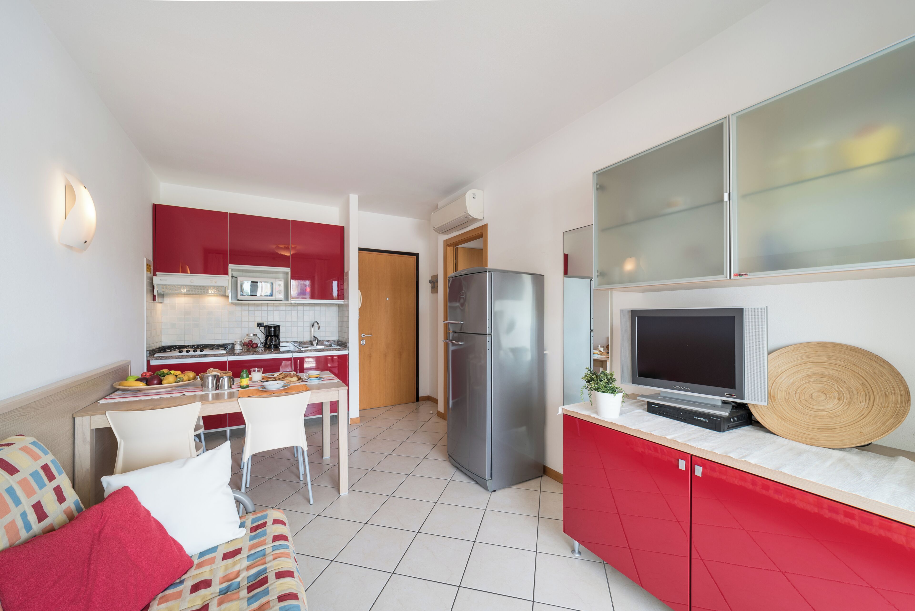 A compact kitchen with a refrigerator, microwave, and a dining area with chairs and a table.