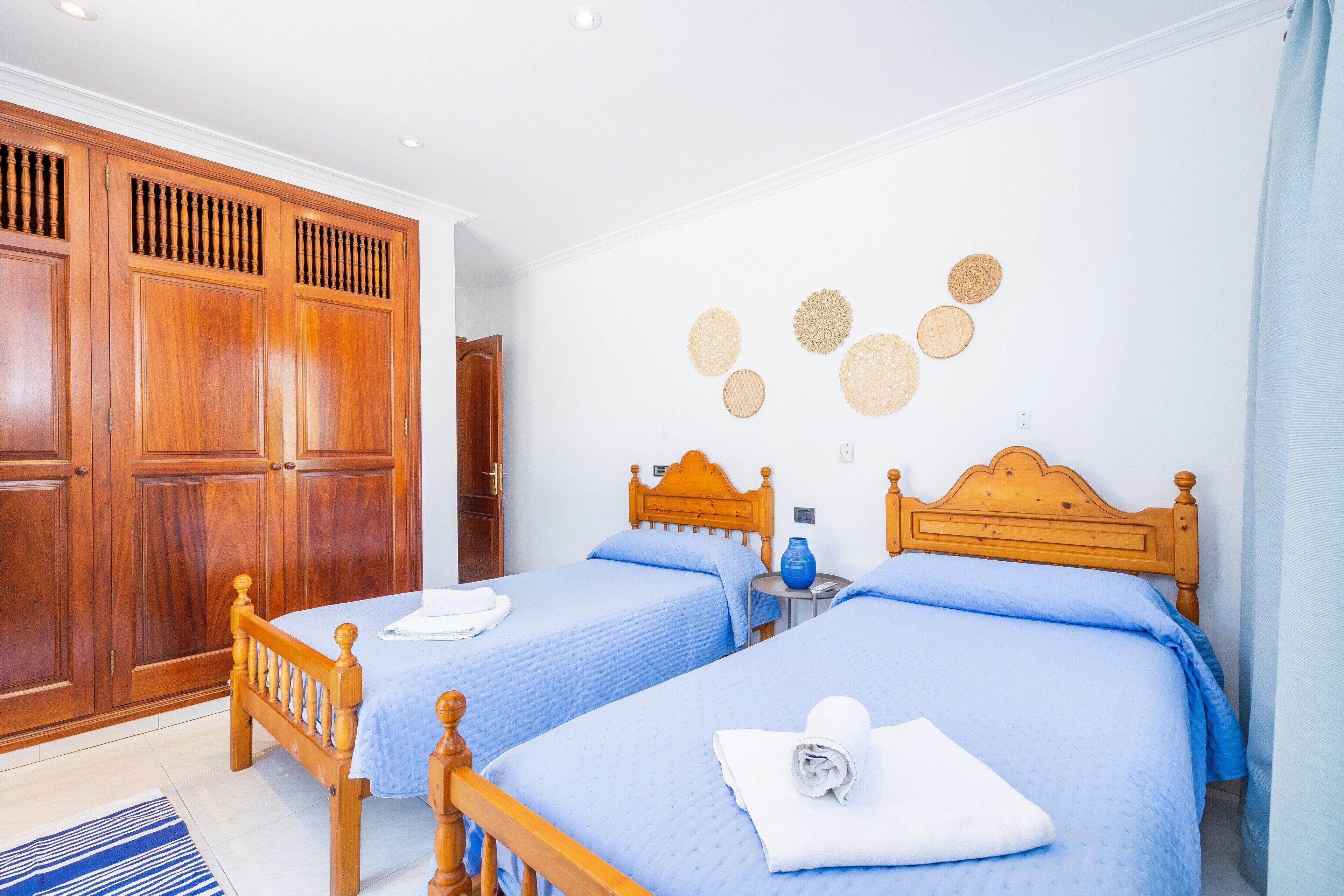 Een kamer met twee bedden, houten kasten en wanddecoratie in een cirkelvorm.