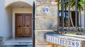 A stone building with a wooden door, a metal gate, and a numbered sign. - Holiday Home 'Llenaire Gran Beach House' with Mountain View, Wi-Fi and Air Conditioning (Pollença)
