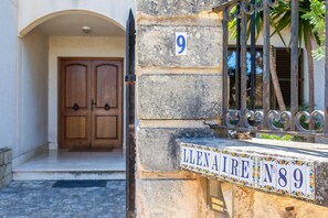 Un bâtiment en pierre avec une porte en bois, un portail en métal et une plaque numérotée.