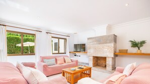A living room with pink sofas, a wooden coffee table, a fireplace, and a TV. - Holiday Home 'Llenaire Gran Beach House' with Mountain View, Wi-Fi and Air Conditioning (Pollença)
