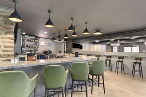 A bar area with a long counter, multiple bar stools, and pendant lighting. - Direct Golf Course Access + Pool. Gym. Restaurant. (Waynesville)